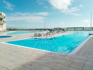 a swimming pool at the surf hotel with chairs and tables at The Surf Studio - Ericeira in Ericeira