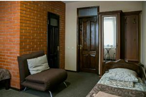 1 dormitorio con cama, silla y pared de ladrillo en Hotel-restaurant complex S Legkim Parom, en Brovary