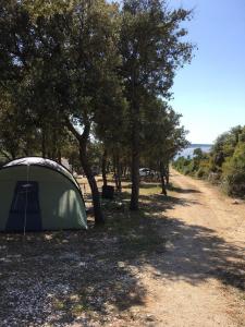 a tent sitting in the shade of trees on a dirt road at Camping Sugar in Mandre