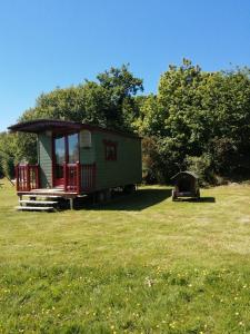 een tiny house in a field with a tent bij Roulotte coin de nature in Lannion