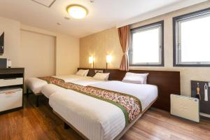 a hotel room with two beds and two windows at Dotonbori Hotel in Osaka
