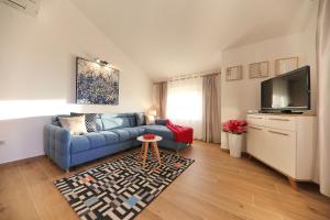 ein Wohnzimmer mit einem blauen Sofa und einem Fernseher in der Unterkunft Apartmani Branka Murter in Murter