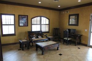 a living room with chairs and a table and windows at Eagle Ford Inn in Floresville +16 photos