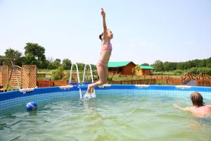 Ein Mädchen springt in ein Schwimmbad in der Unterkunft Agrodomek in Łowyń