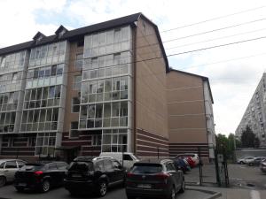 a building with cars parked in a parking lot at Apartments near Metalist Stadium in Kharkiv