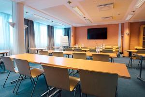 a classroom with tables and chairs and a flat screen tv at Hotelliravintola Kumpu in Outokumpu