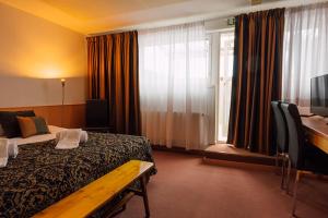 a hotel room with a bed and a desk and a window at Hotelliravintola Kumpu in Outokumpu