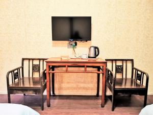 einen Tisch mit 2 Stühlen und einen TV an der Wand in der Unterkunft Shaoxing Laotaimen Luxun Native Place Youth Hostel in Shaoxing