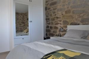 a bedroom with a bed and a stone wall at Pedra da Lan - una casita de piedra in Cangas de Morrazo