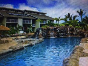a swimming pool with a waterfall in front of a house at The Cliffs Club at Princeville in Princeville