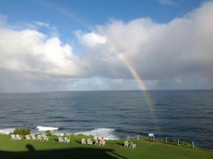 a rainbow over the ocean with a group of chairs at The Cliffs Club at Princeville in Princeville