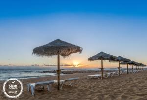 a row of umbrellas and chairs on a beach at Dom Jose Beach Hotel (Plus) in Quarteira