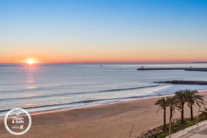 a sunset over the ocean with palm trees on a beach at Dom Jose Beach Hotel (Plus) in Quarteira