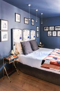 - une chambre avec un grand lit aux murs bleus dans l'établissement La Femme d'à Côté, à Saint-Valery-sur-Somme