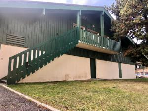 um edifício com uma escada verde ao lado dele em L'Aire des montagnes em Bolquere Pyrenees 2000