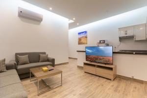 a living room with a couch and a flat screen tv at الوادي للوحدات السكنية in Riyadh Al Khabra