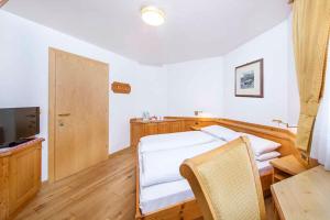 um quarto com uma cama, uma mesa e uma televisão em Hotel Garni Morene em Selva di Val Gardena