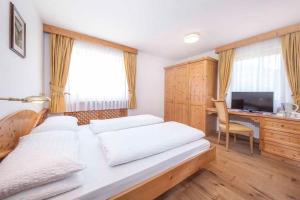 a bedroom with a bed and a desk with a computer at Hotel Garni Morene in Selva di Val Gardena