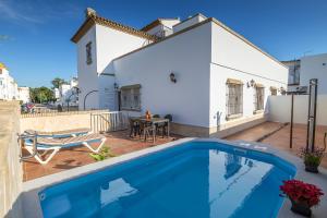 a swimming pool in front of a white house at Chalet adosado Atalaya P in Conil de la Frontera