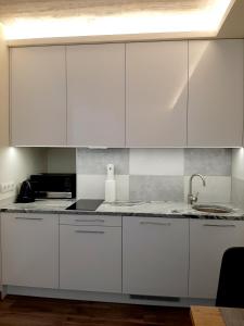 uma cozinha com armários brancos e um lavatório em Smeltale apartament 3 em Klaipėda
