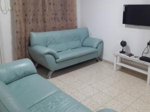 a living room with a blue couch and a television at Yaakov's Apartment in Migdal Ha‘Emeq