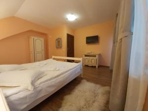 Vila Piscul Ursului في بريدال: غرفة نوم بسرير ابيض وسجادة بيضاء