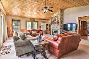 a living room with leather furniture and a stone fireplace at Log Cabin with Deck and Hot Tub 5 Mi to Dollywood! in Pigeon Forge