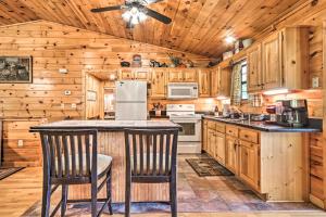 a kitchen with wooden cabinets and a ceiling fan at Log Cabin with Deck and Hot Tub 5 Mi to Dollywood! in Pigeon Forge