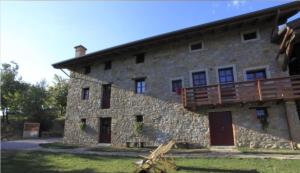 - un grand bâtiment en pierre avec un balcon dans l'établissement Agriturismo Ronchi Rò, à Lonzano