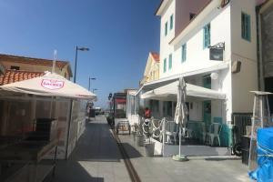 a street with tables and umbrellas next to a building at Lavra Sea & Sun Beach Apartment (up to 4 guests) in Lavra