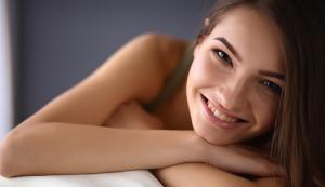 a young woman laying on a bed with her arms at Altos Hotel & Spa in Avranches