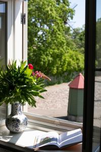 a window sill with a book and a vase with a flower at Silbernagel Apartment in Kuressaare
