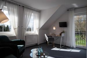 a living room with a couch and a desk and two windows at Hotel & Restaurant Am Alten Rhin in Neuruppin