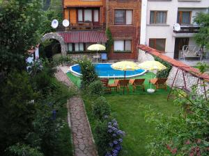 a backyard with a swimming pool and chairs and umbrellas at Семеен хотел Калина Family hotel Kalina Говедарци in Govedartsi