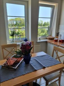 una mesa de comedor con un jarrón de flores. en Ferienwohnung Warnemünde - Landhaus Immenbarg, en Diedrichshagen