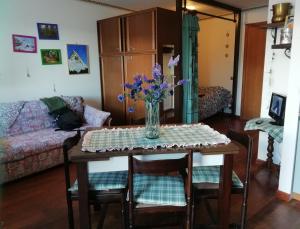 salon ze stołem z wazonem kwiatów w obiekcie Il Nido - Delizioso alloggio presso il centro con vista spettacolare e giardino w mieście Sauze dʼOulx