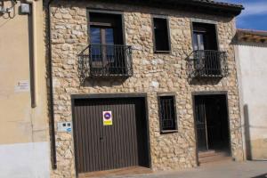 un edificio de piedra con 2 puertas y 2 ventanas en CASA RURAL ALTA YUBERIA en Berlanga de Duero