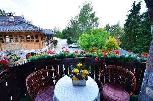 a table and chairs on a balcony with flowers at Villa Miris Dunja in Zlatibor