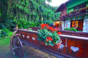 a wooden bench with flowers on it in front of a house at Villa Miris Dunja in Zlatibor
