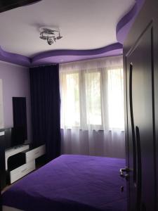 Dormitorio púrpura con cama y ventana en Viktoria Paradise, en Devin