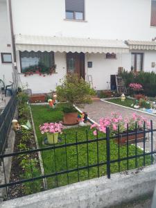 une clôture devant une maison ornée de fleurs roses dans l'établissement Leoni, à Santa Giustina