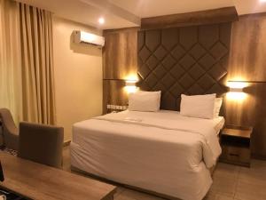 a hotel room with a large bed and a desk at Lit Suites in Abuja