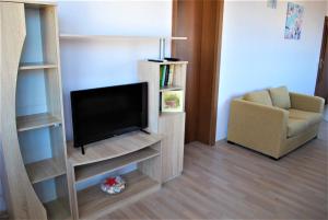 a living room with a television and a chair at Family Hotel Amore in Byala