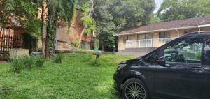 TERTIUS LODGE في نيلسبروت: سيارة متوقفة في العشب امام المنزل