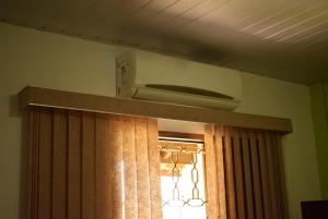 a air conditioner above a window with a curtain at Pousada Colonetti in Lindóia