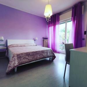 ヴェローナにあるAi Giardini Roomsの紫の壁のベッドルーム1室、ベッド1台、窓が備わります。