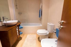ein Badezimmer mit Toilette, Waschbecken und Badewanne in der Unterkunft Flat Casino Beach Figueira da Foz - Moderno & Ótima Localização! in Figueira da Foz + 13 Fotos