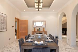 a dining room with a wooden table and chairs at Maison Privee - Prvt Pool & Beach! in Luxury Palm Jumeirah Villa in Dubai