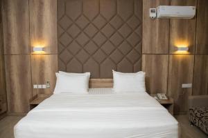 a bedroom with a large white bed with two pillows at Lit Suites in Abuja