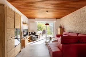 Ferienwohnung Liomena في Lehmen: غرفة معيشة مع أريكة حمراء وسقف خشبي